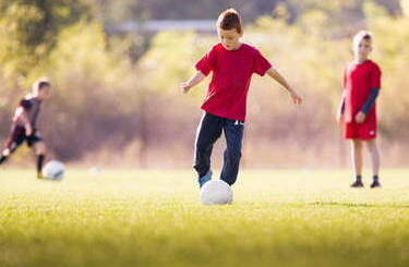 Chłopcy grają na boisku w piłkę nożną.